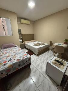 a room with two beds and a table and chairs at SUITE banheiro privativo & 2 QUARTOS banheiro social PERTO DO GERALDÃO,ARENA PERNAMBUCO,UNIVERSO, UFPE,AEROPORTO-AFOGADOS- RECIFE in Recife