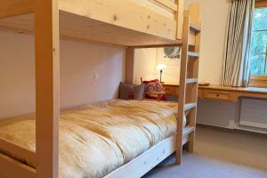 a bedroom with a bunk bed and a desk at Panorama Apartment Gotschnablick 1-6 Pers in Klosters