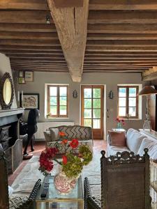 a living room with a couch and a table with flowers at MAISON LA TRANQUILITÉ by Frans & Ricardo in Saint-Didier-sur-Arroux