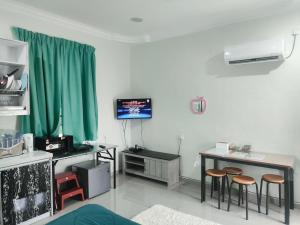 a living room with green curtains and a table and stools at Dikmad Studio Room Bukit Mentok, Kemaman in Cukai
