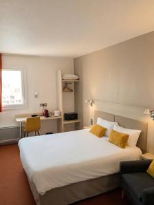a bedroom with a large white bed and a desk at Brit Hotel Confort Deltour Mende in Mende