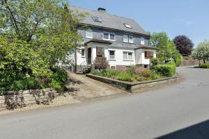 a large white house with a stone wall at Haus Schnettler mit Sauna in Bestwig