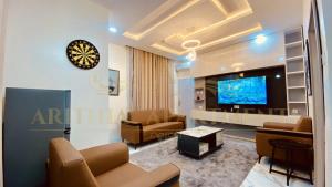 a living room with couches and a tv and a clock at Arithia Apartments in Mama