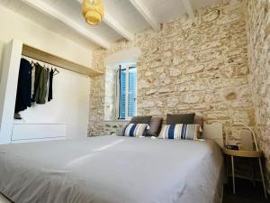 a bedroom with a large bed and a stone wall at Maison Bleu Katomeri in Katomérion