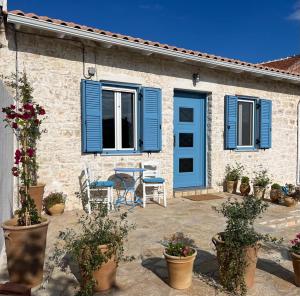 a house with blue shutters and a patio with plants at Maison Bleu Katomeri in Katomérion