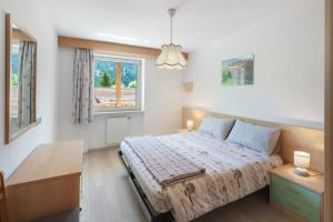 a bedroom with a bed and a desk and a window at Appartamenti Lella in Vigo di Fassa
