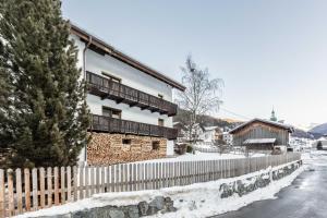 a house with a fence in the snow at Appartement Tschol in Flirsch