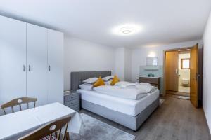 a white bedroom with two beds and a table at Appartement Tschol in Flirsch +24 photos