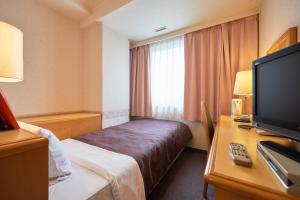 um quarto de hotel com uma cama e uma televisão de ecrã plano em Hotel Select Inn Aomori em Aomori