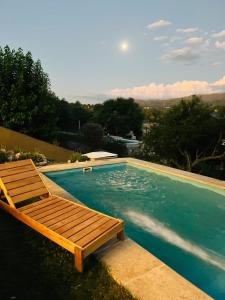 ein Schwimmbecken mit einer Holzbank daneben in der Unterkunft ClCabañas in Huerta Grande