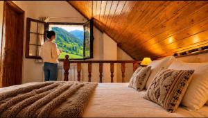 a woman looking out the window of a bedroom at Apartamentos rurales La Pornacal I y La Pornacal II in Villar de Vildas