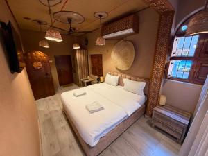a bedroom with a large bed with white sheets at Aldar Inn - نزل الدار in Nizwa