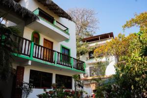a white building with green balconies and trees at Bungalows Puerta de Sol in Brisas de Zicatela