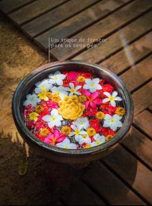 a bowl full of flowers on a wooden table at Pousada Casa das Rendas in Praia de Moitas