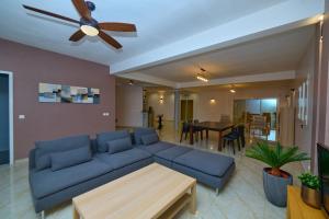 a living room with a blue couch and a ceiling fan at Villa de détente "Tombosoa" avec vue sur la baie de Diego-Suarez in Antsiranana