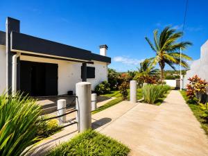 a white house with a palm tree and a sidewalk at Villa de détente "Tombosoa" avec vue sur la baie de Diego-Suarez in Antsiranana