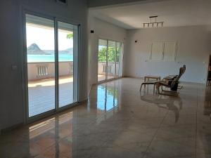 a living room with glass doors and a table and chairs at Villa de détente "Tombosoa" avec vue sur la baie de Diego-Suarez in Antsiranana