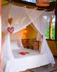 a bedroom with a bed with hearts hanging from it at Pousada Casa das Rendas in Praia de Moitas +14 photos