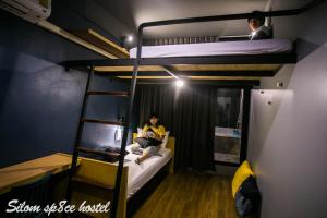 a person sitting on a bunk bed reading a book at Silom Space Hostel in Bangkok