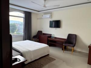 a hotel room with a bed and a desk and a window at Kamaksha Palace in Sundarnagar