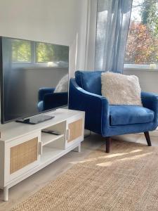 a living room with a blue chair and a tv at Alder House Lytham in Lytham St Annes