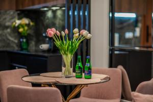 a table with two bottles of beer and a vase of flowers at Apartament Bursztynowa Komnata 116 Stegna nad morzem in Stegna