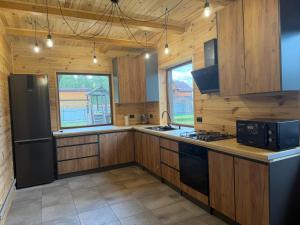 a kitchen with wooden cabinets and a black refrigerator at Pulmo Rest House in Pulʼmo