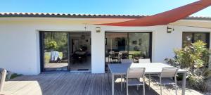 a patio with a table and chairs on a deck at Maison GINKGO in Hourtin