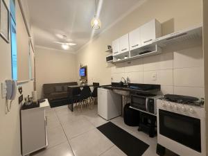 a kitchen with white appliances and a living room at Self check-in Garagem Ar 13 min ABQM in Araçatuba