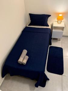 a bed with a blue blanket and two slippers on it at Self check-in Garagem Ar 13 min ABQM in Araçatuba