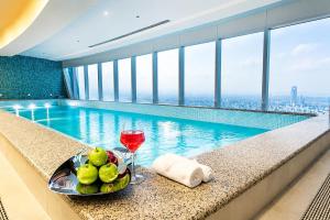 a bowl of fruit and a glass of wine next to a swimming pool at شقة برج رافال Rafal Tower in Riyadh