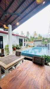 a patio with a wooden table and a swimming pool at Thara Inn Villa in Dickwella