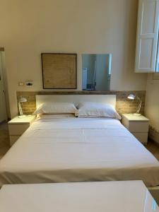a large white bed in a room with two lamps at Gabici Suite Ravenna in Ravenna