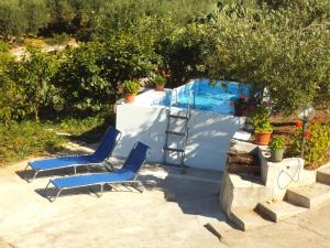 two blue chairs sitting next to a swimming pool at Valle Verde 3 Clima & Wi-Fi in Castellammare del Golfo