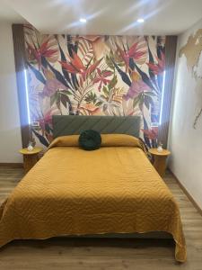 a bedroom with a yellow bed with a floral wallpaper at Aer in Caserta