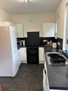 a kitchen with white appliances and black counter tops at Kilnhill in Hawick +6 photos