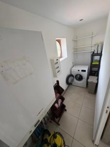 a kitchen with a white wall and a washing machine at Le chalet de l Escaut in Bantouzelle +2 photos