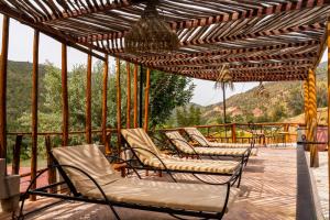 a group of chairs sitting on a patio with a pergola at Dar l'eau Vive in Bine el Ouidane