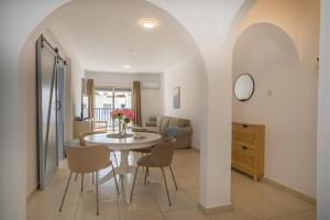 a dining room and living room with a table and chairs at Aphrodite Breeze Paphos Gardens in Paphos