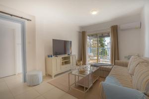 a living room with a couch and a tv at Aphrodite Breeze Paphos Gardens in Paphos