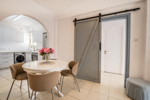 a kitchen with a white table and chairs and a door at Aphrodite Breeze Paphos Gardens in Paphos