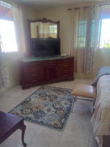 a bedroom with a dresser with a tv and a rug at Tambell Haven in Runaway Bay
