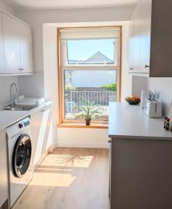 a kitchen with a washing machine and a window at Glentorran in Campbeltown