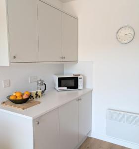 a white kitchen with a microwave and a bowl of fruit at Glentorran in Campbeltown