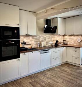 a kitchen with white cabinets and black appliances at Apacs Villa in Ráckeve