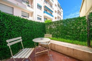 a table and chairs sitting next to a green hedge at Hôtel Comté de Nice in Beaulieu-sur-Mer