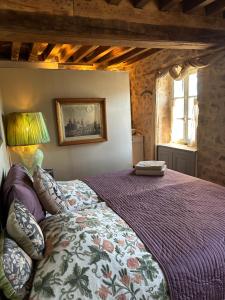 a bedroom with a large bed with a purple comforter at MAISON LA TRANQUILITÉ by Frans & Ricardo in Saint-Didier-sur-Arroux