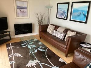 a living room with a leather couch and a fireplace at John's Luxury Seafront Apartment in Newcastle