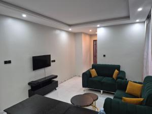 a living room with green furniture and a flat screen tv at CozyStay Homes in Kampala