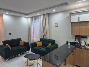 a living room with two green chairs and a kitchen at CozyStay Homes in Kampala